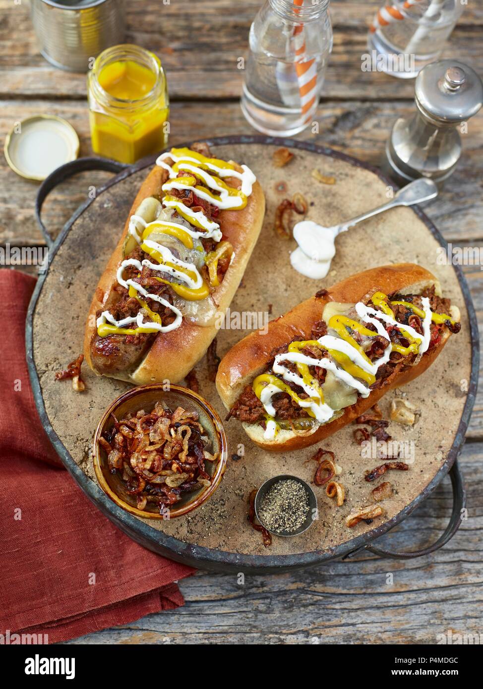 Chili Hot Dogs garniert mit gebratenen Zwiebeln, Senf und Mayonaise Stockfoto