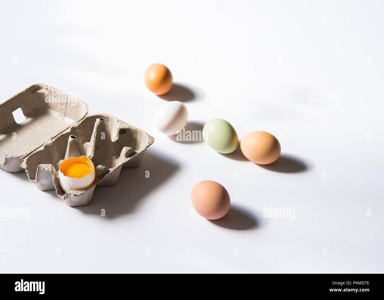 Frische Hühnereier neben einem Ei Box mit einem Gesprungenen open Ei Stockfoto