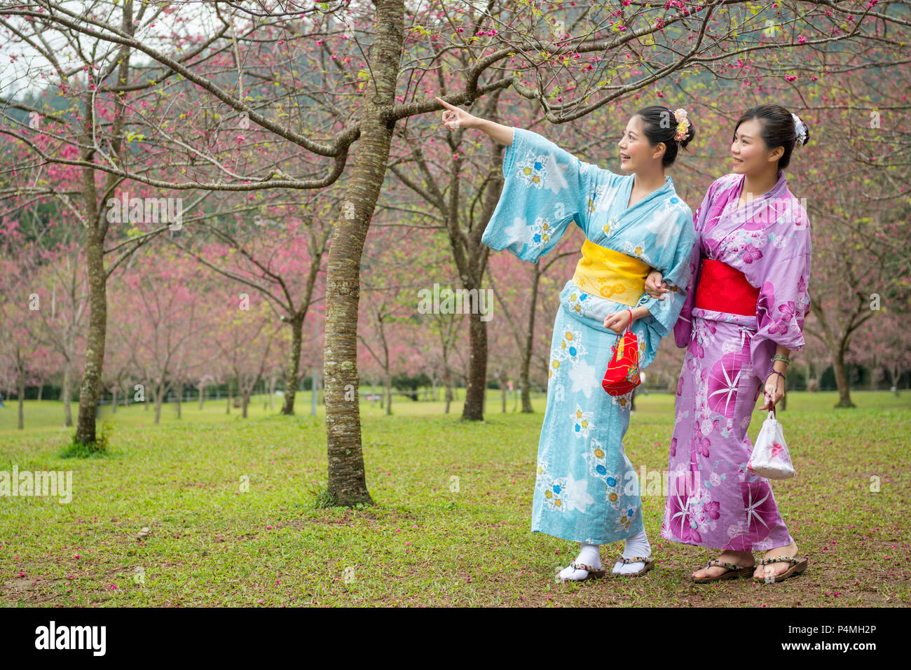Zwei asiatische Frau Seite an Seite und Hand in Hand zusammen und suchen für die Richtung, in die das Mädchen zeigen. Stockfoto