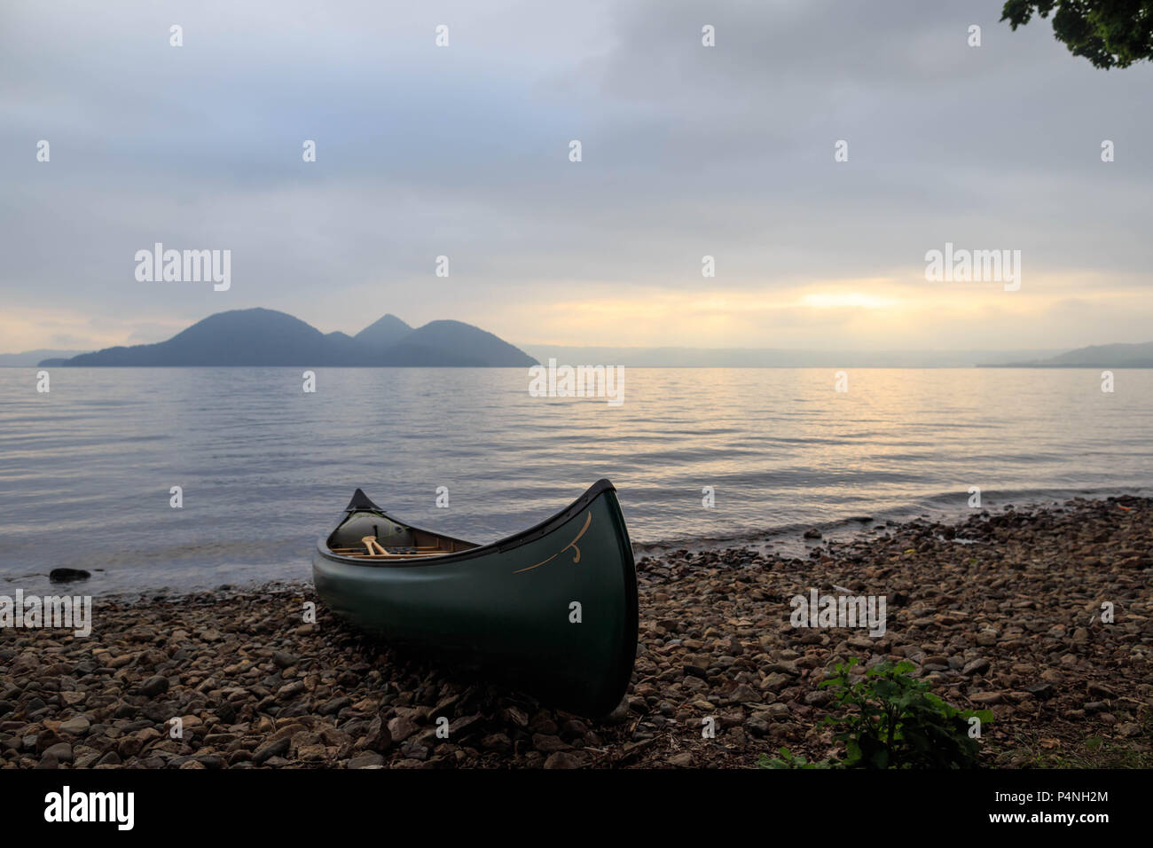 Kanu sitzt am Strand von Crater Lake bei Sonnenuntergang in Hokkaido, Japan Stockfoto