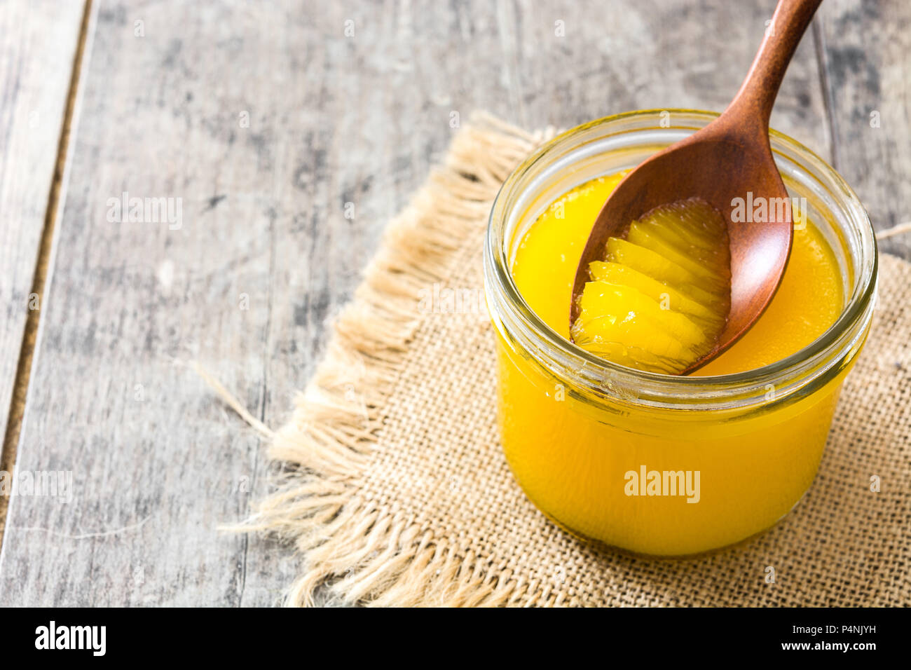 Ghee oder Butterschmalz in Glas und Löffel aus Holz auf Holz- Tabelle. Ansicht von oben. Copyspace Stockfoto