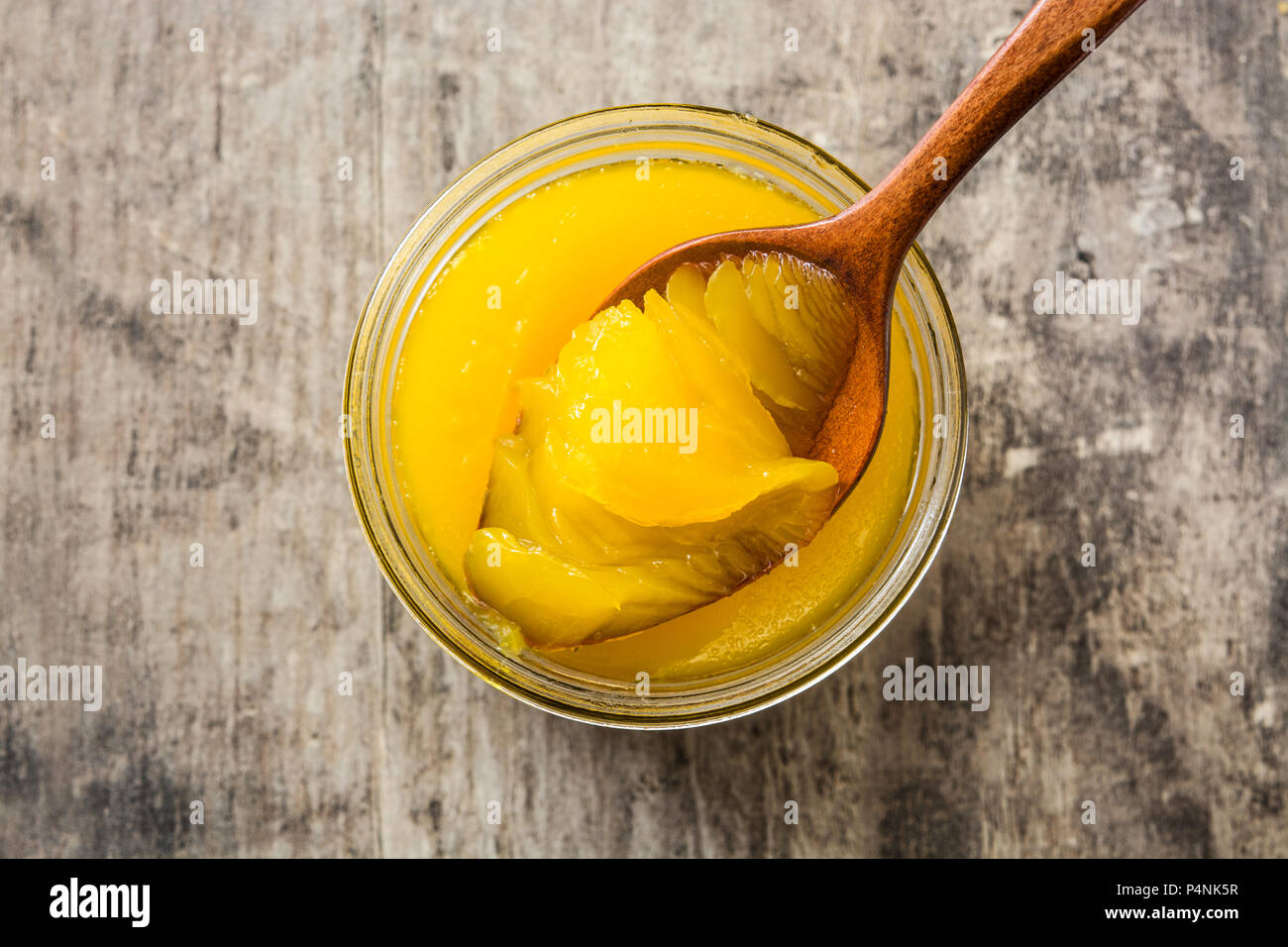 Ghee oder Butterschmalz in Glas und Löffel aus Holz auf Holz- Tabelle. Ansicht von oben Stockfoto