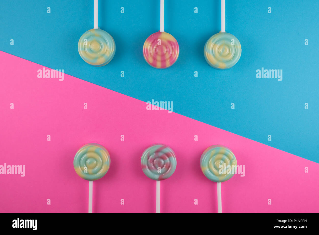 Sortiment an farbenfrohen Lutscher auf rosa und blau gefärbten Hintergrund. süße Speisen Konzept Stockfoto
