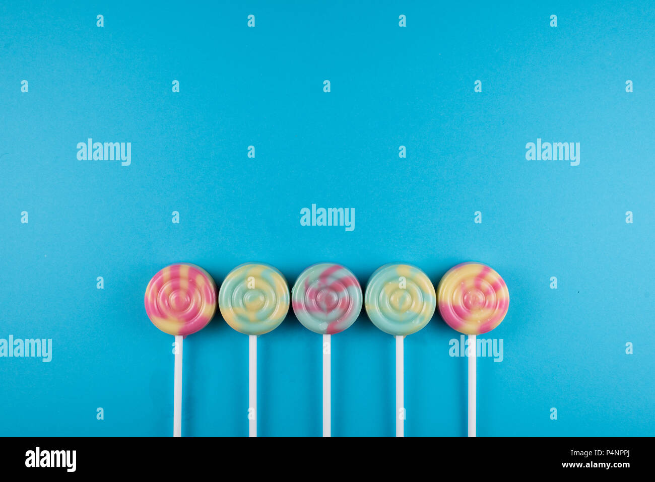 Sortiment an farbenfrohen Lutscher über blau gefärbten Hintergrund. süße Speisen Konzept Stockfoto