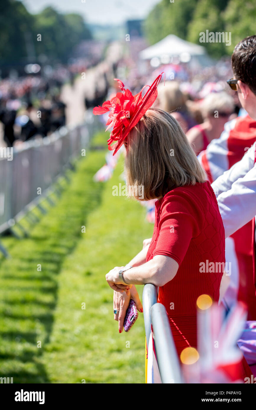 Eine Frau in einem roten Kleid und roten fascinator Uhren die königliche  Hochzeit von Seiner Königlichen Hoheit, Prinz Harry und Frau Meghan Markle  auf dem Langen in Windsor entfernt. Sie verband Tausende