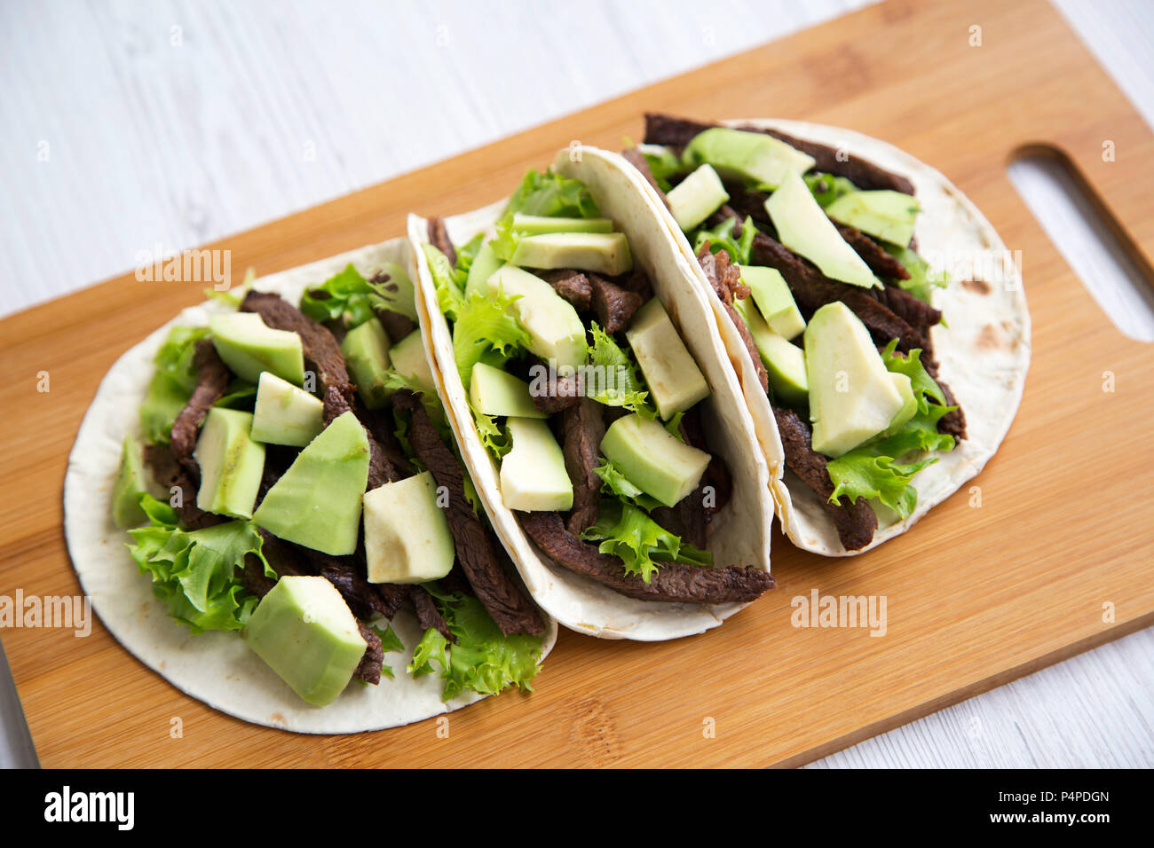 Drei mexikanische Tacos auf der Bambus Board auf einem weißen Holz- Hintergrund. Nahaufnahme. Stockfoto