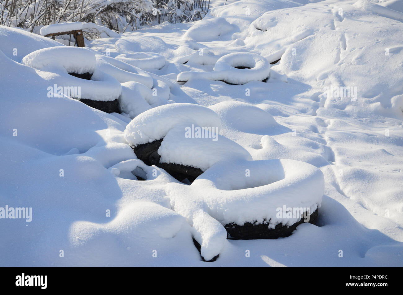 Benutzt und weggeworfen Autoreifen liegen auf der Seite der Straße, mit einer dicken Schicht Schnee bedeckt. Stockfoto