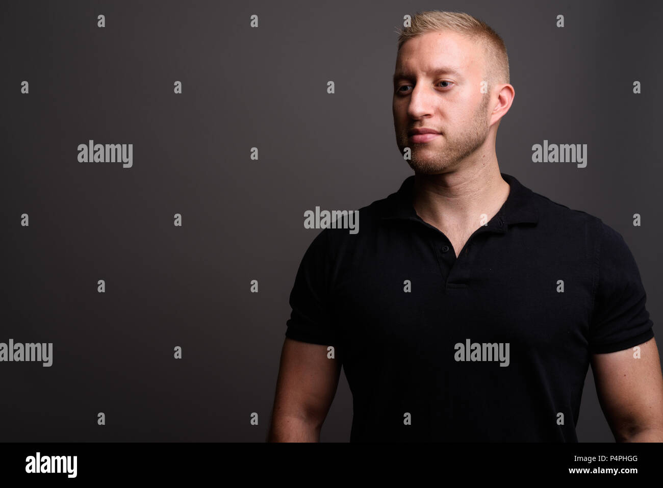 Mann mit blondem Haar mit schwarzen polo shirt gegen Grau backgr Stockfoto