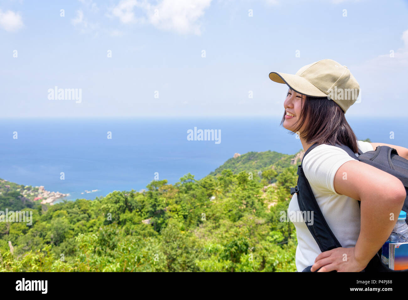 Frauen Tourist mit einem Rucksack tragen Cap glücklich ständigen Blick auf schöne Natur Landschaft, blauen Himmel und Meer von hoher malerischer Aussichtspunkt auf Koh Tao in S Stockfoto