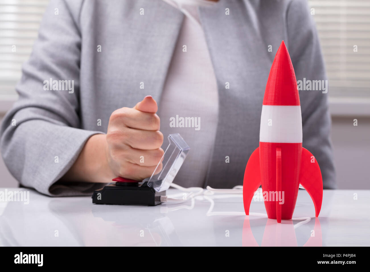 Die Geschäftsfrau Hand mit Raketen durch Drücken der roten Taste Stockfoto