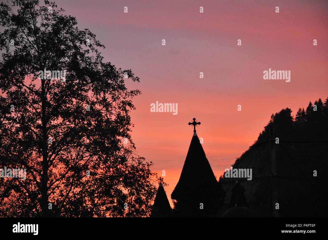 Die Silhouette eines Kirchturms, einem großen Baum und Wald auf goldenen Stunden Himmel Hintergrund Stockfoto