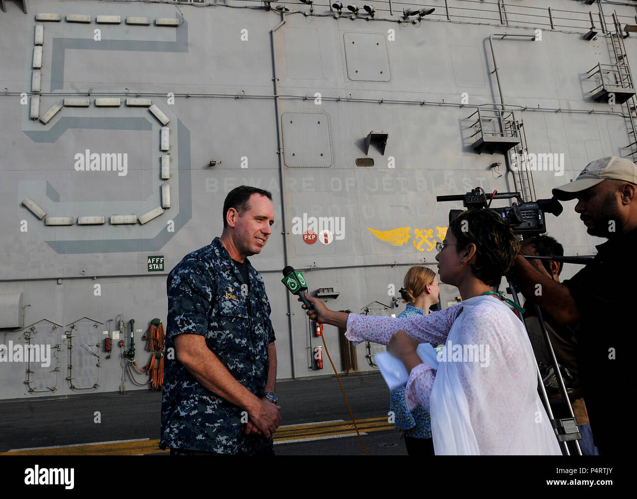 Us-Marine Kapitän David Schnell, Links, kommandierender Offizier der USS Peleliu LHA (5), ist auf der Peleliu Flight Deck während einer pakistanischen Medien Besuch an Bord des Schiffes 12.08.2010, in den USA 5 Flotte Verantwortungsbereich interviewt. Peleliu übermittelte seine erste Welle von Lieferungen an Land 12.08.2010, ein Stützelement und Schaltstelle für Navy und Marine Corps Heavy lift Flugzeuge zu etablieren. Stockfoto