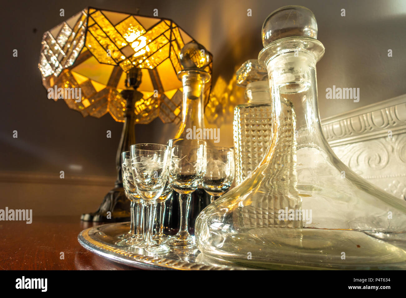 Eine Reihe von Wein Gläser und Dekanter auf Tisch mit einem Vintage Style Tischleuchte im Hintergrund. Stockfoto