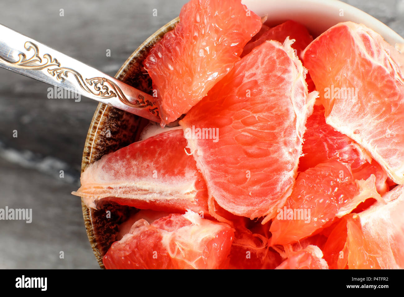 Auf kleinen Porzellan Schüssel mit Löffel Detail, voller rosa Grapefruit in Stücke schneiden. Stockfoto