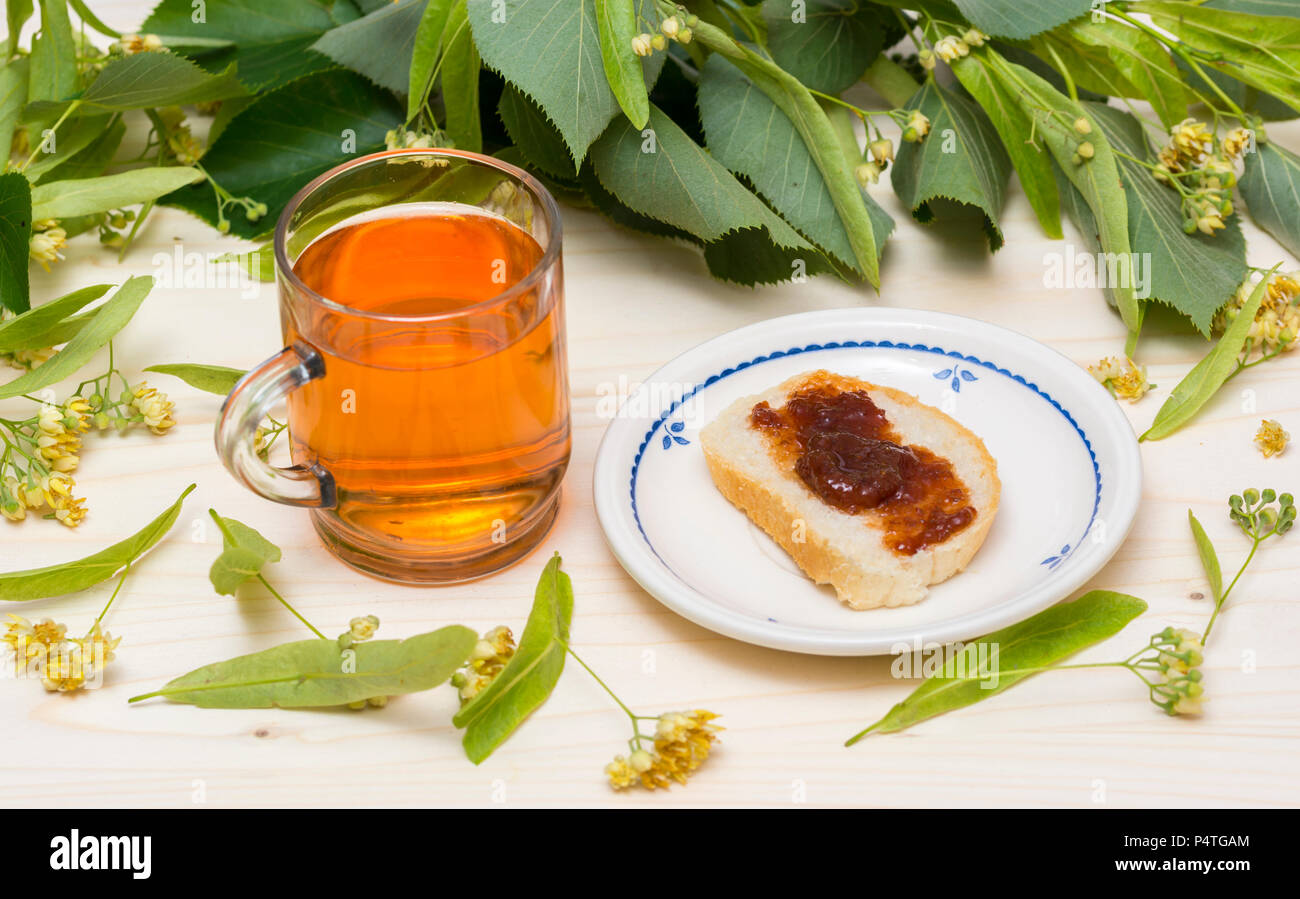 Linden Tee in ein Glas Schale Blüten und Linden Blätter, Scheibe Brot mit Marmelade Stockfoto