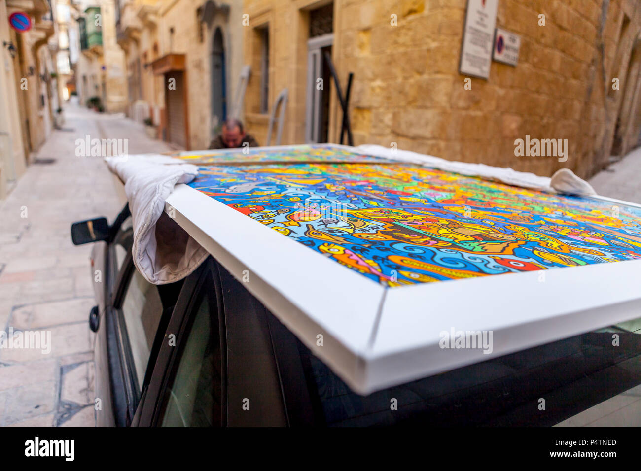 VALETTA, MALTA - Februar 4, 2016: Mann bindet ein Stück kunst auf seinem Auto Stockfoto