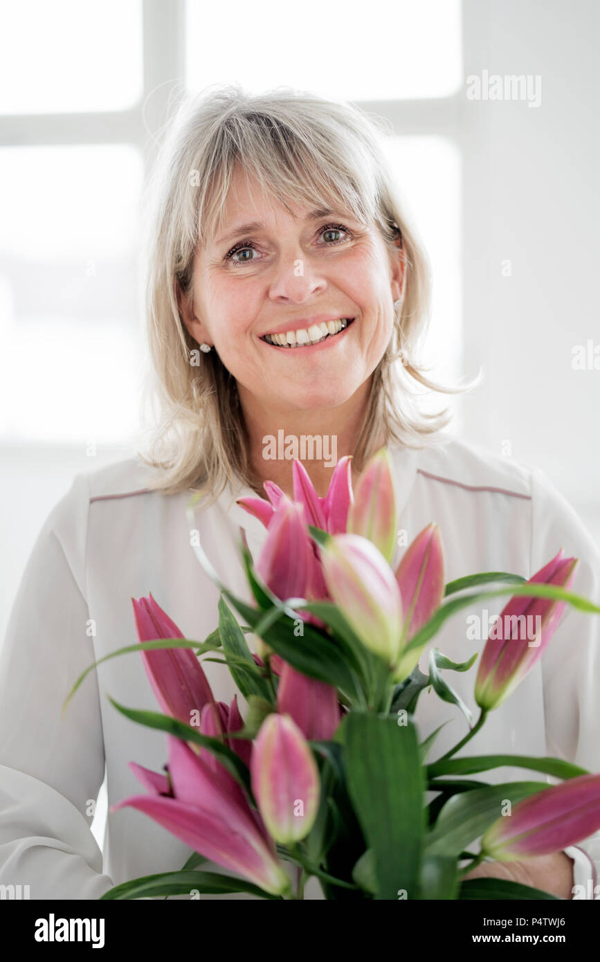 Portrait von lächelnden reife Frau mit Blumen Stockfoto