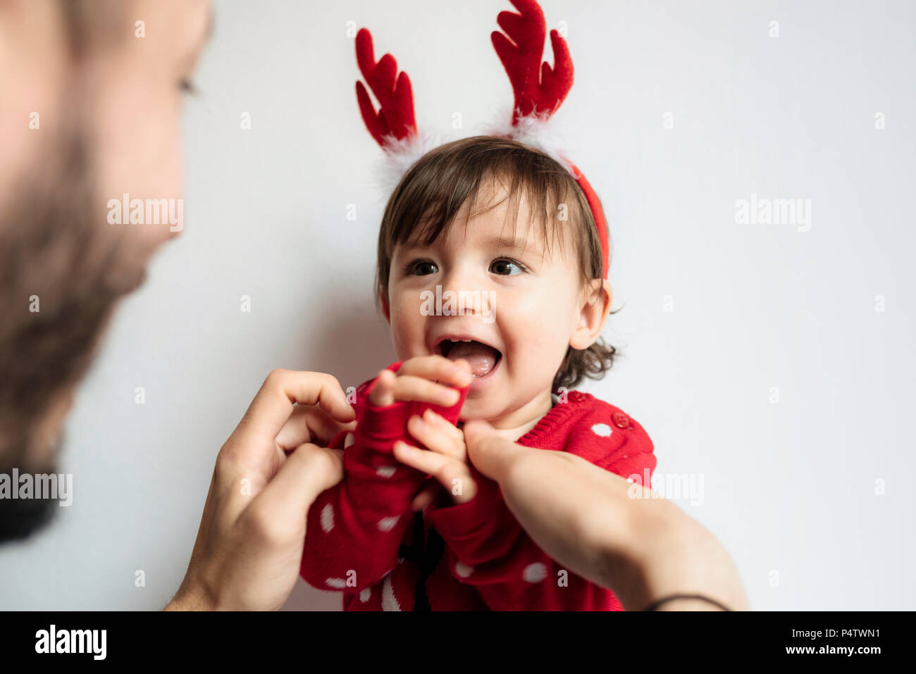 Portrait von lachendes Baby Mädchen mit Rentier Geweih Stirnband anziehen, die von ihrem Vater. Stockfoto