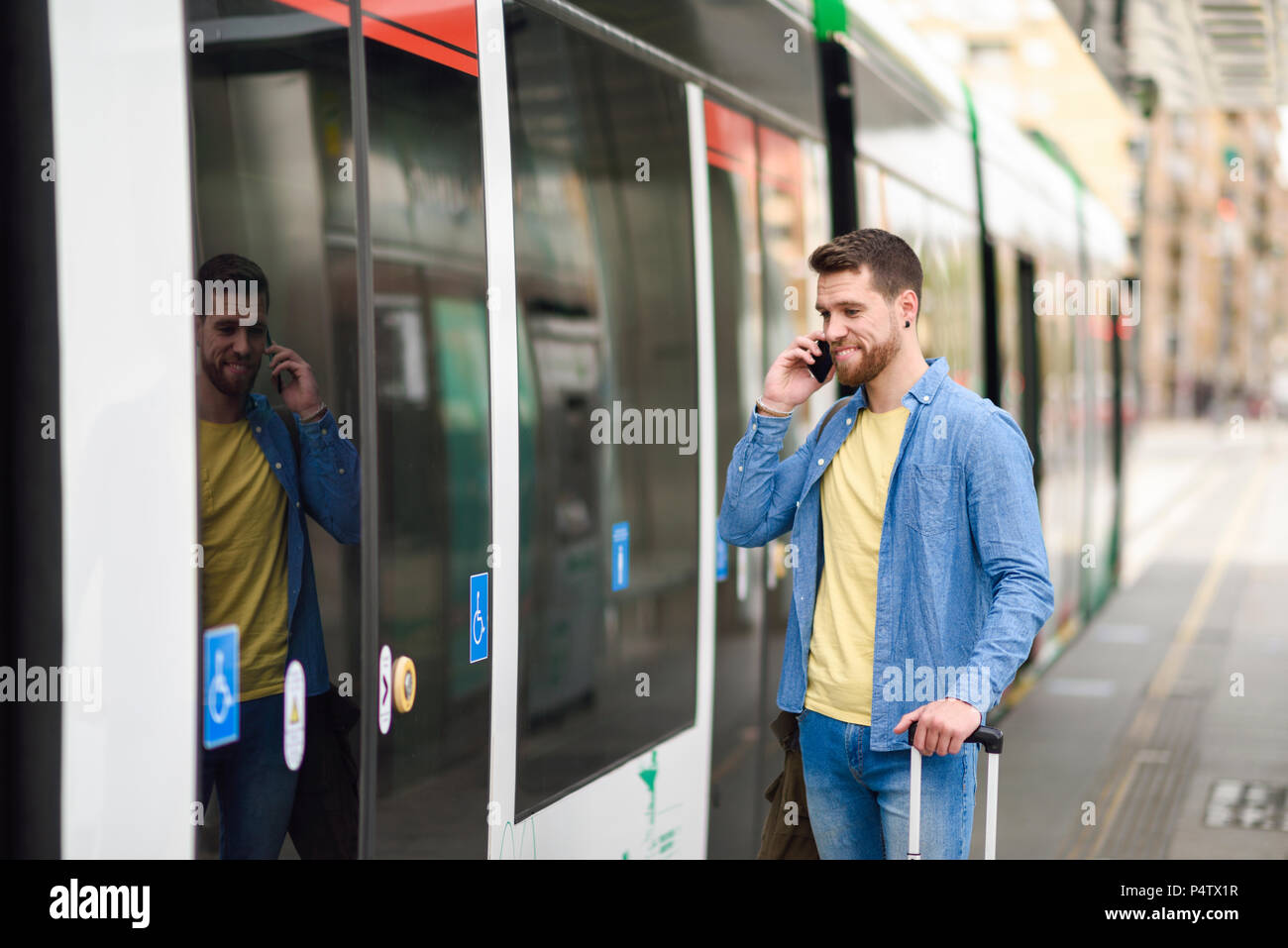 Junger Mann mit Smartphone vor Straßenbahn Stockfoto