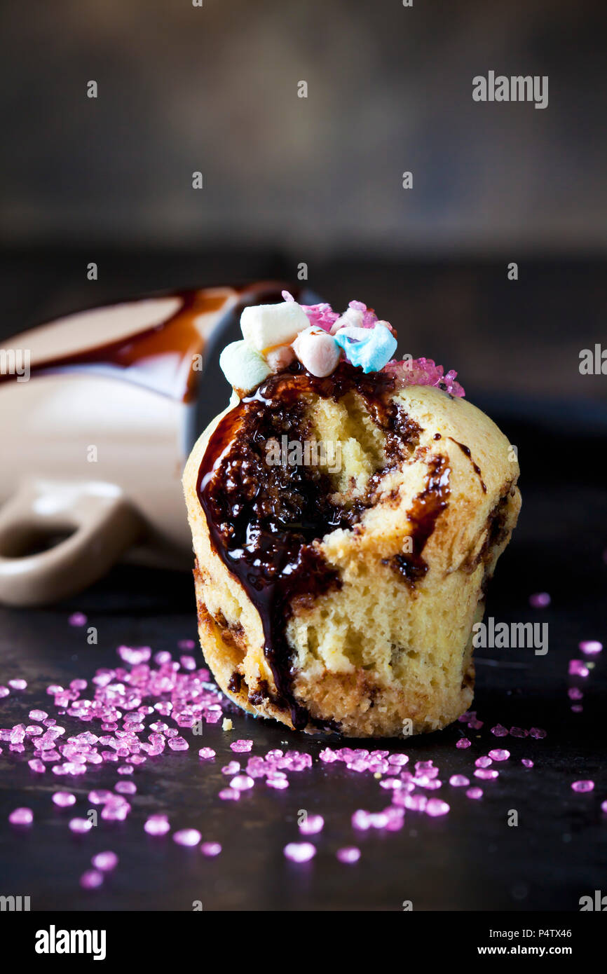 Vanille Cup Cake mit Schokoladensauce, Marshmallows und rosa Zucker Granulat Stockfoto