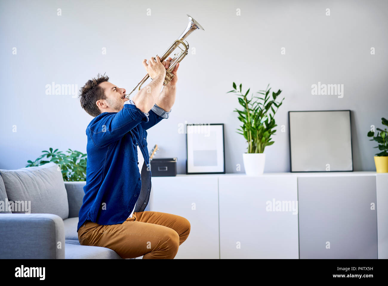 Mann sitzt auf der Couch spielen Trompete Stockfoto
