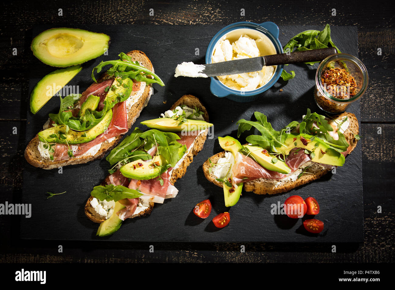 Zwiebel Brot mit Frischkäse, Parma Schinken, Avocado, Rucola, Thymian und Tomaten Stockfoto