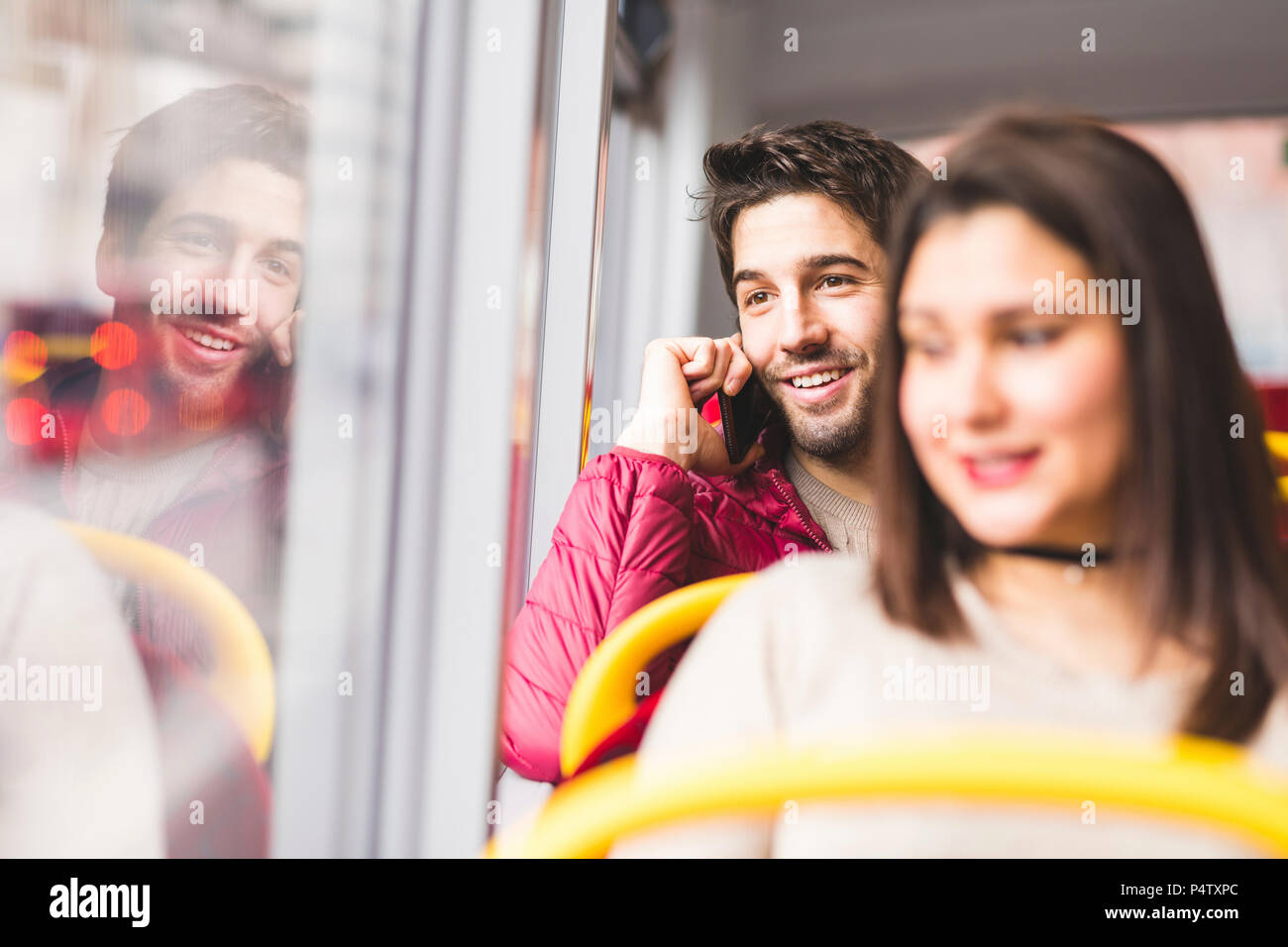 UK, London, Portrait von lächelnden jungen Mann am Telefon in einem Bus Stockfoto
