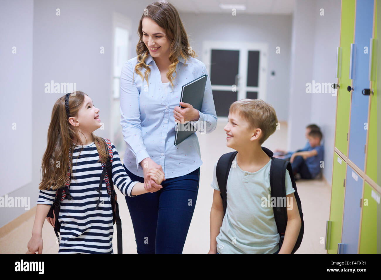 Lächelnd Schüler und Lehrer Hand in Hand auf Korridor in der Schule Stockfoto