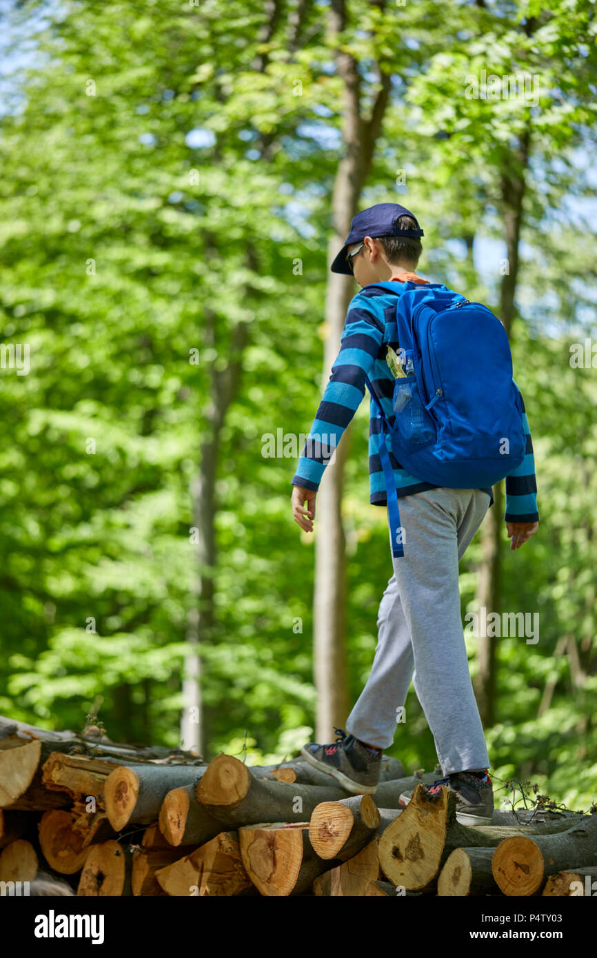 Junge mit Rucksack Balancieren auf Logs im Wald Stockfoto