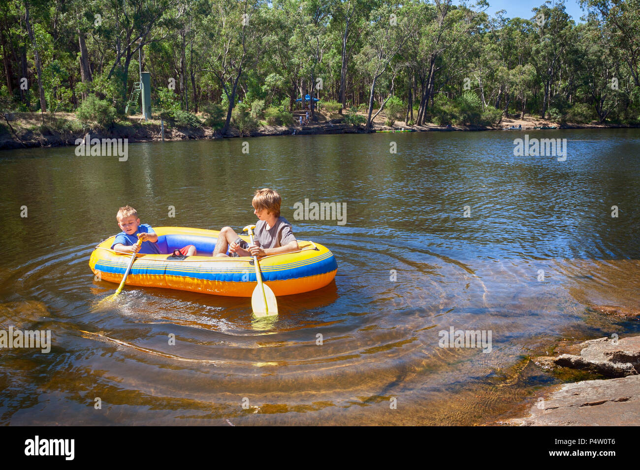 Zwei Jungen Paddeln in einem Schlauchboot auf einer australischen Fluss. Stockfoto