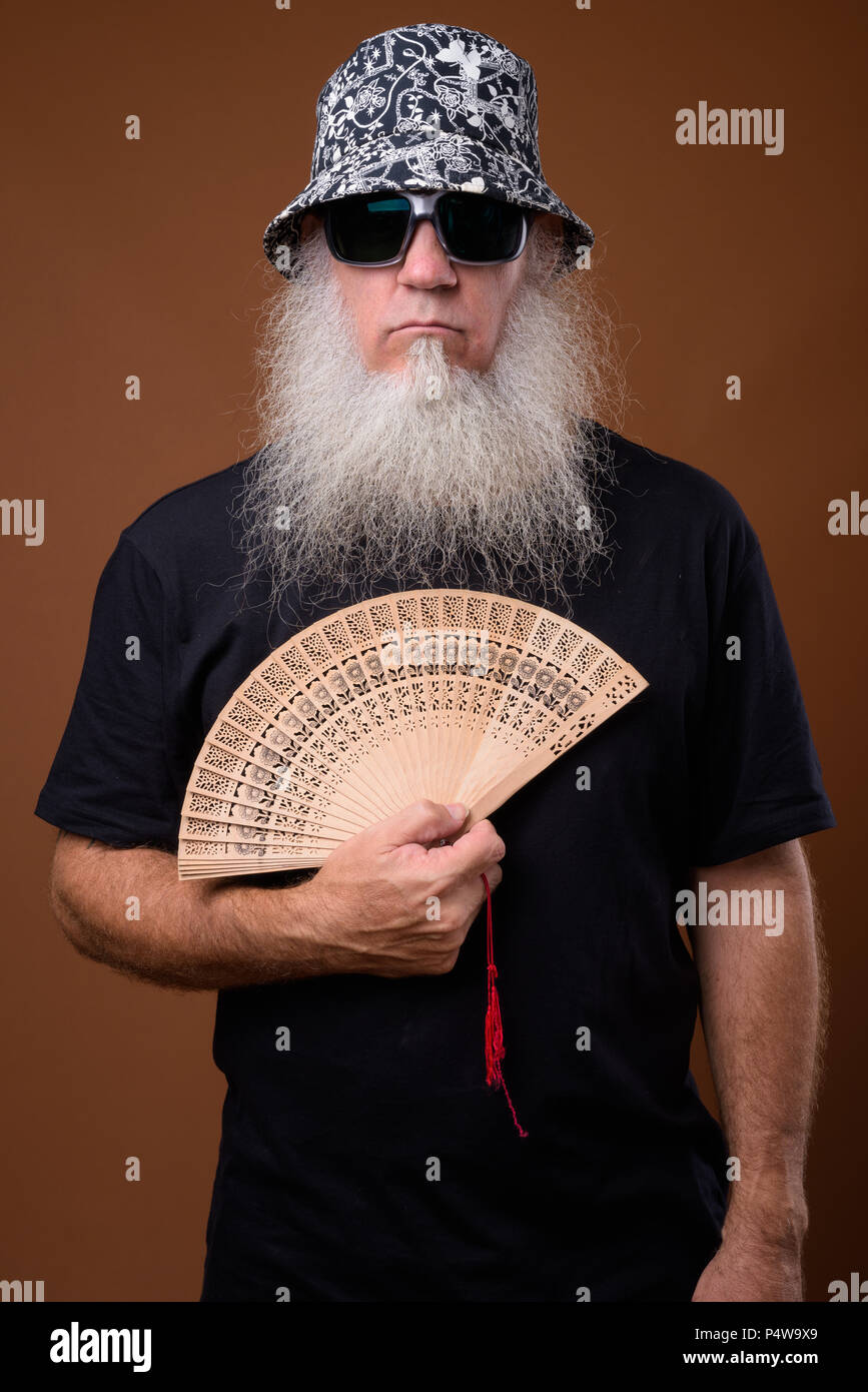 Reifer Mann mit langen grauen Bart gegen braunen Hintergrund Stockfoto