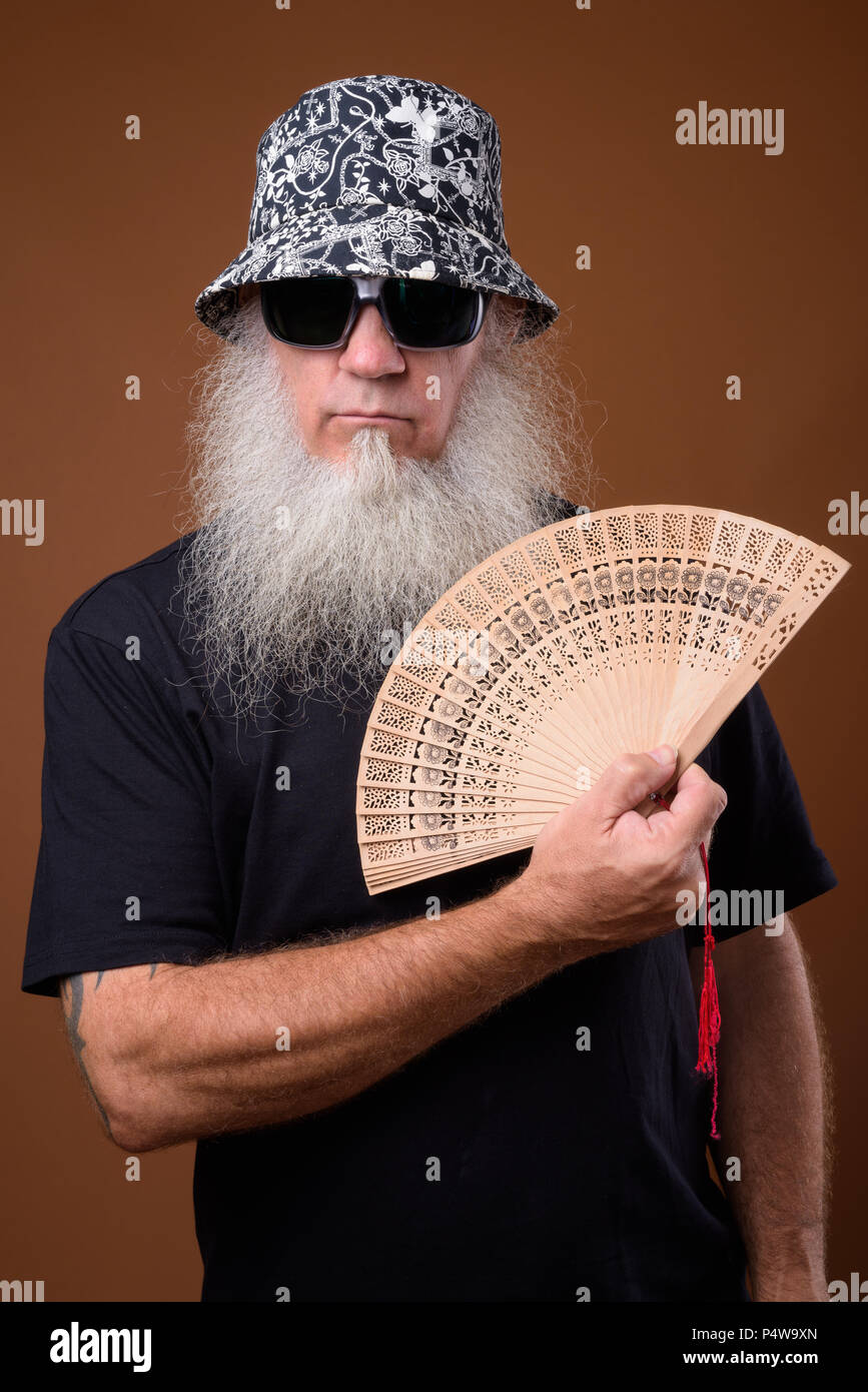 Reifer Mann mit langen grauen Bart gegen braunen Hintergrund Stockfoto