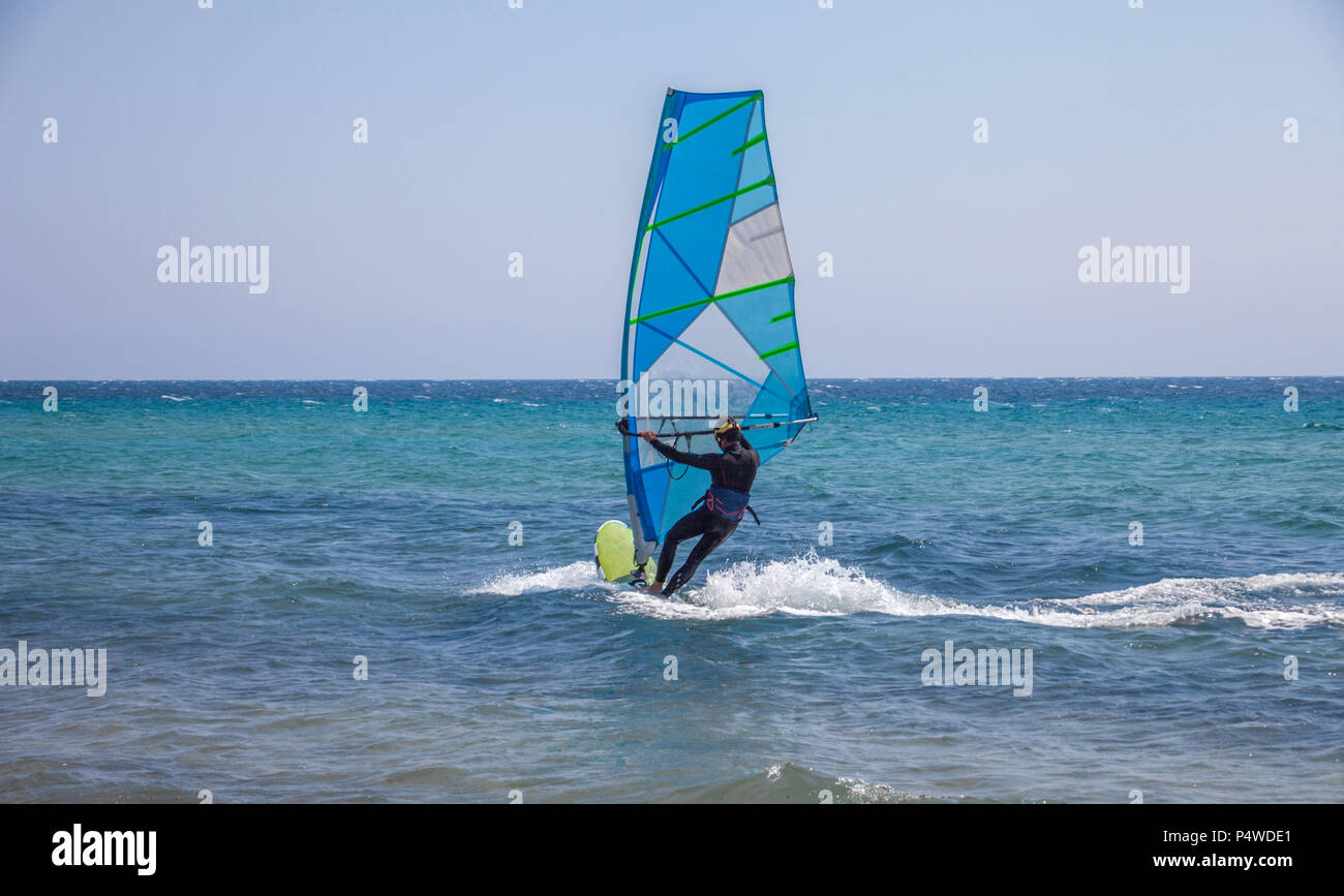 Ein Mann das Ausgleichen der Segeln. Starke Wellen gleiten unter dem Wasser sport Equipment. Windsurfen Enthusiast in Aktion. Die Förderung der Aktivität in der b Stockfoto