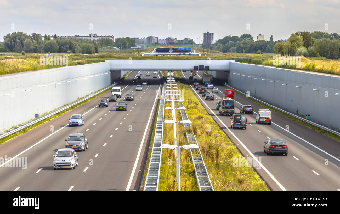 Am Nachmittag pendelt der Verkehr auf der Autobahn a4 in der Nähe von Den Haag Gegend Randstad. Autobahn Kreuzung aquaduct Tunnel mit städtischen Gebiet von Rotterdam im Hintergrund, Ne Stockfoto