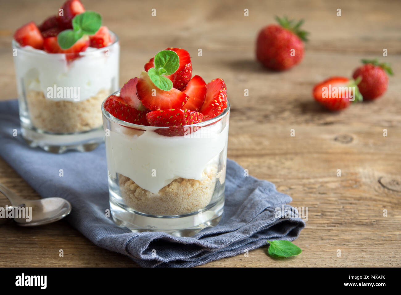 Strawberry trifle Mini Dessert in Gläsern mit frischen Erdbeeren und Sahne Käse auf Holz- Hintergrund. Gesunde hausgemachte potrion Dessert. Stockfoto