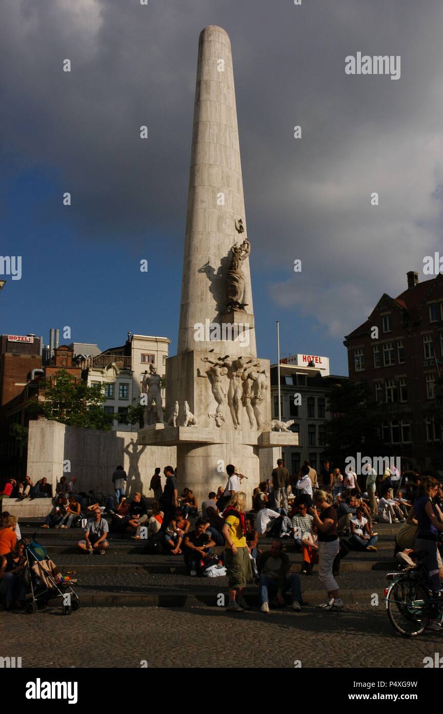 Leute sitzen auf dem Dam Platz am Fuße des National Monument, Obelisk errichtet 1956 von J. S. Oud und John Raedecker, zum Gedenken an die gefallenen Soldaten im Zweiten Weltkrieg. Amsterdam. Holland. Stockfoto