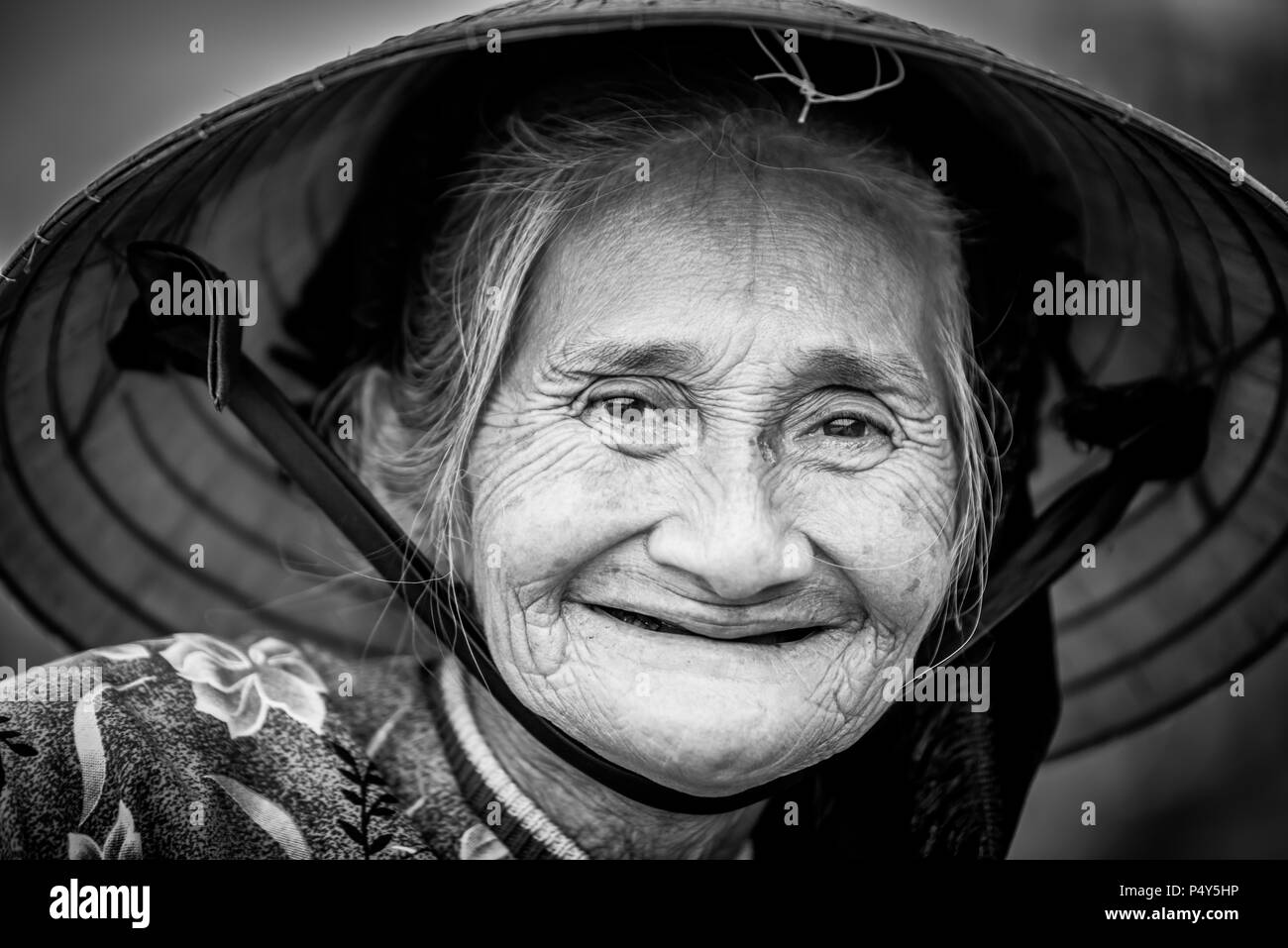 Alte freundliche Frau mit vietnamesischen Strohhut Stockfoto