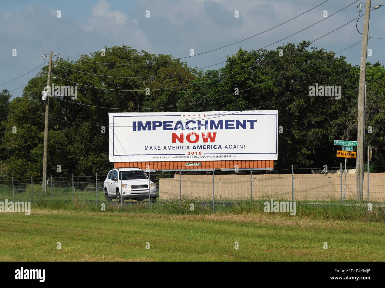 Florida, USA. 23. Juni 2018. Fährt ein Auto eine Plakatwand in Lakeland, Florida am 23. Juni 2018 fordert die Amtsenthebung von US-Präsident Donald Trump. Am Straßenrand Zeichen wurde vor Kurzem auf einer Straße parallel stark gereist zu I-4 von Mad Dog PAC, ein Maryland platziert progressive Gruppe, als Teil einer landesweiten Kampagne zur Finanzierung Werbetafeln targeting Trump und andere GOP Politiker gewidmet. Die Gruppe wird eine identische Billboard früh dieses Jahr zwei Meilen von Mar ist Trumpf - a - Lago Immobilien in Palm Beach, Florida. (Paul Hennessy/Alamy) Credit: Paul Hennessy/Alamy leben Nachrichten Stockfoto