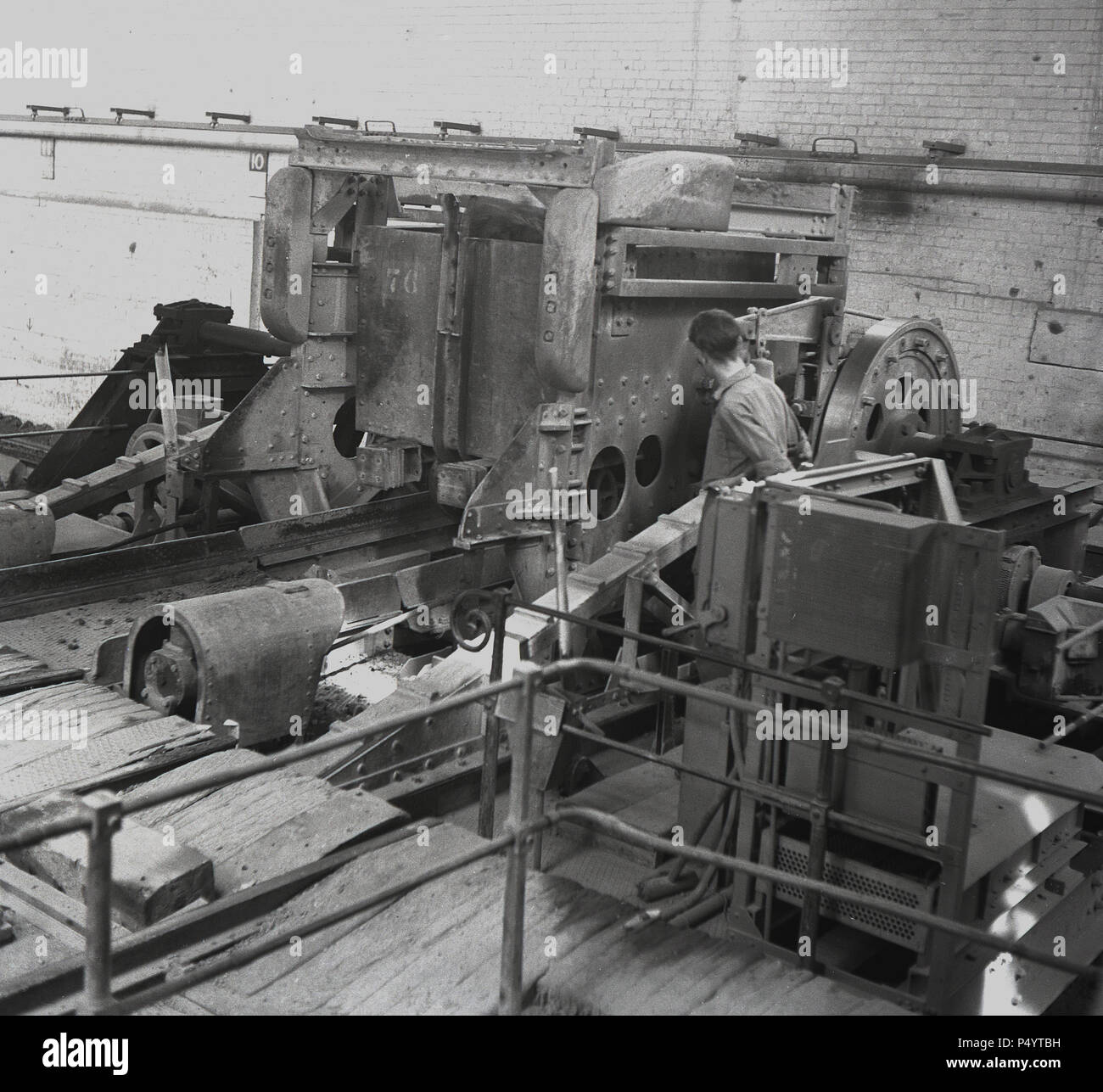 1950er Jahre. Historisch, ein männlicher Arbeiter an einer Maschine, perphaps eine Mühle des Rohmaterials, des Schlammsteins oder des Felsens. Die Ziegelei der London Brick Company im Nachkriegsengland wurde zur größten Ziegelei der Welt, die 8 Dörfer im Marston Vale miteinander verbindet, darunter das berühmte 'Modelldorf' von Stewartby, Die den Beschäftigten Wohnraum, Sport und soziale Einrichtungen, sowie eine Kirche, Schule, Laden und Hausarzt zur Verfügung gestellt. Stockfoto