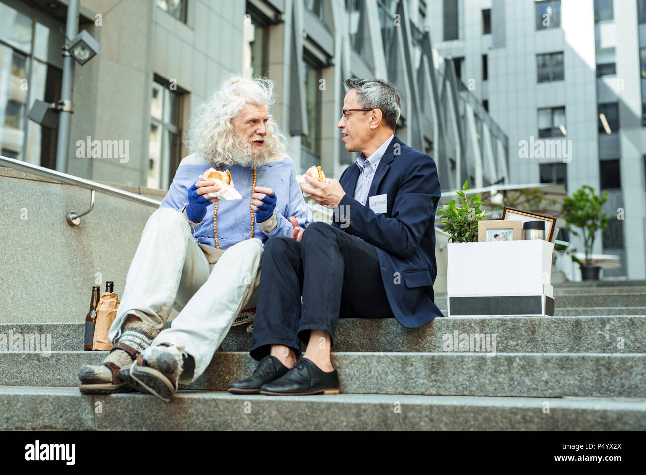 Faltige Mann mit Brille und schöne blaue T-Shirt essen Burger Stockfoto