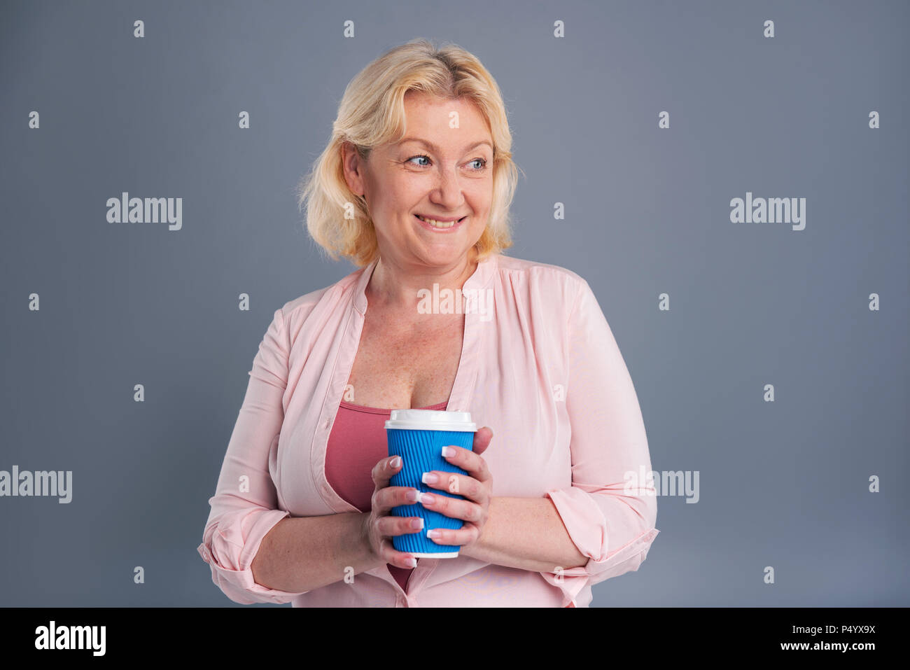 Fröhliche Frau mittleren Alters, die blaue Kaffeetasse Stockfoto