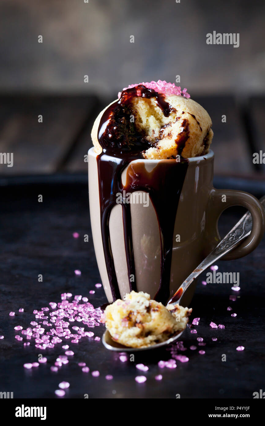 Vanille Cup Cake mit Schokoladensauce und rosa Zucker Granulat Stockfoto