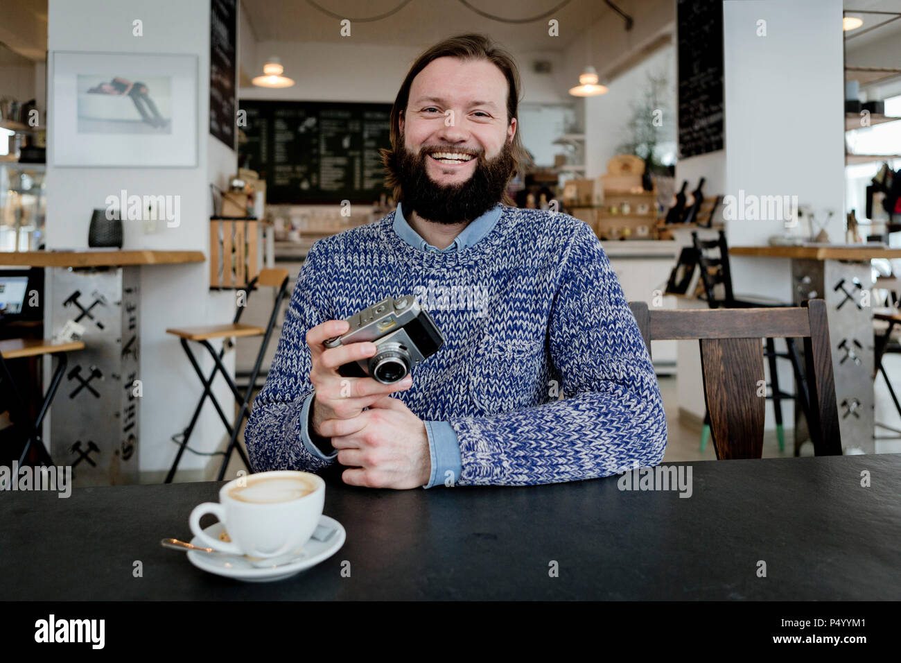 Mann mit Bart im Cafe sitzen, halten alte Kamera Stockfoto
