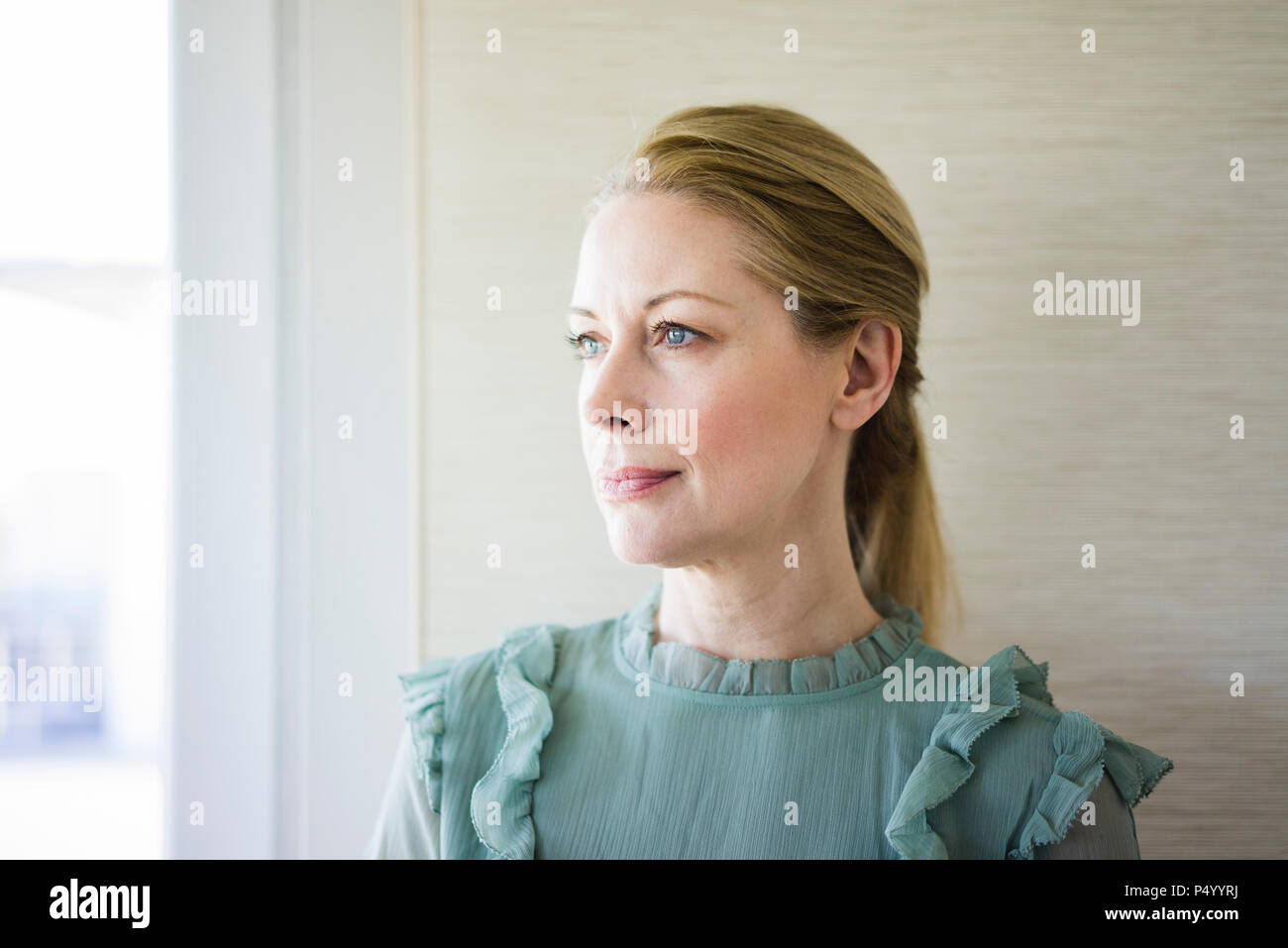 Portrait von Blonde reife Frau Blick aus Fenster Stockfoto