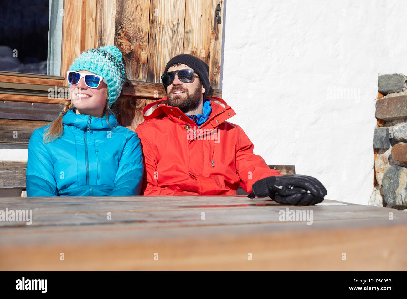 Paar Sonnenbaden im Winter an der hölzernen Berghütte Stockfoto