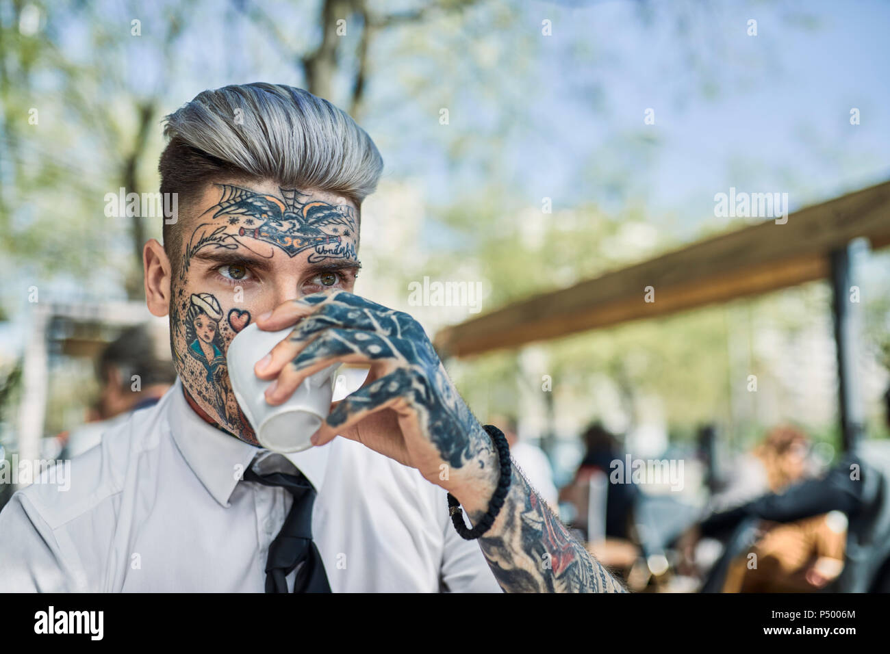 Junge Unternehmer mit tätowierten Gesicht, trinken Kaffee Stockfoto