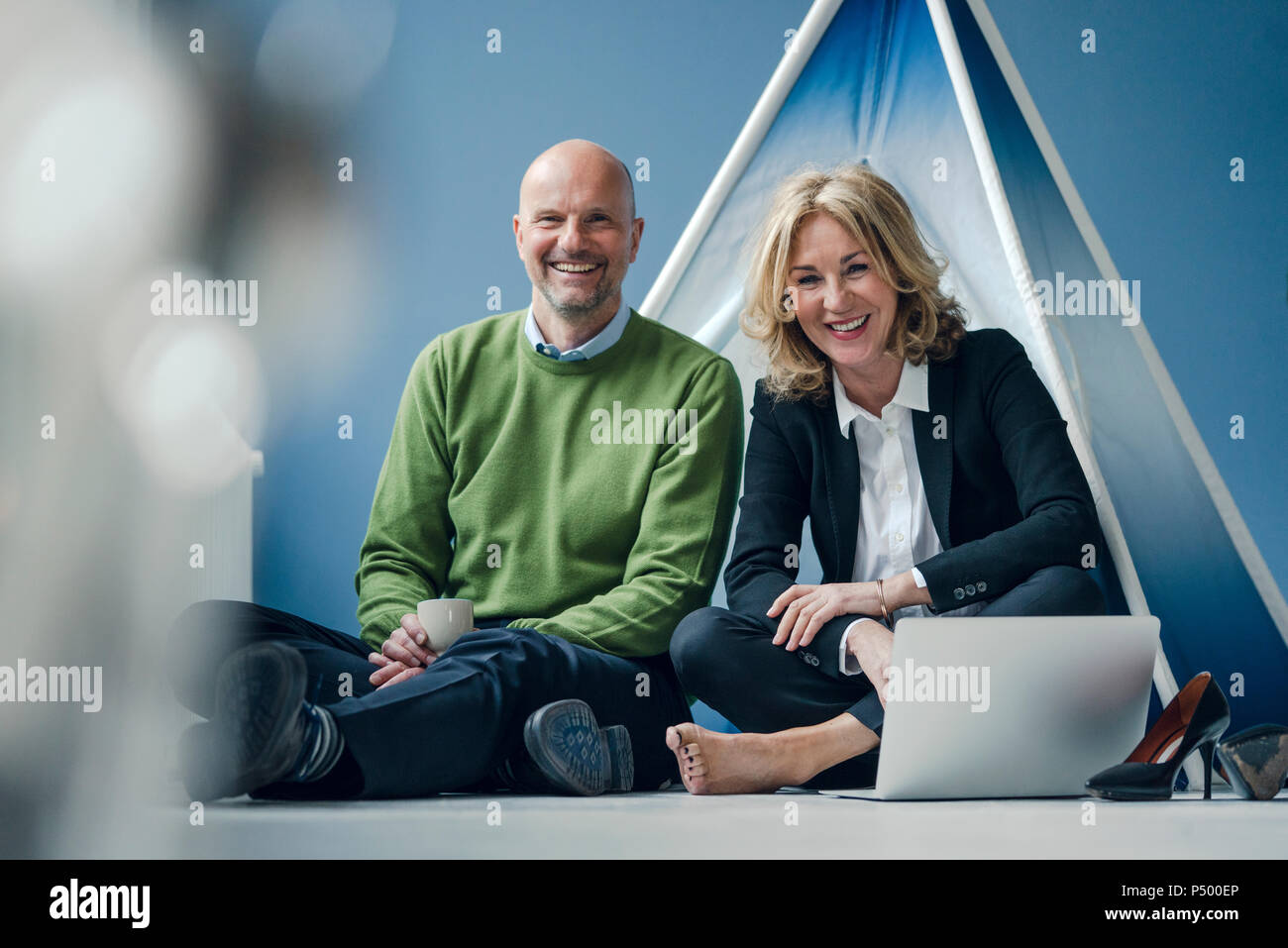 Happy Geschäftsmann und Geschäftsfrau im Tipi drinnen sitzt mit Laptop Stockfoto