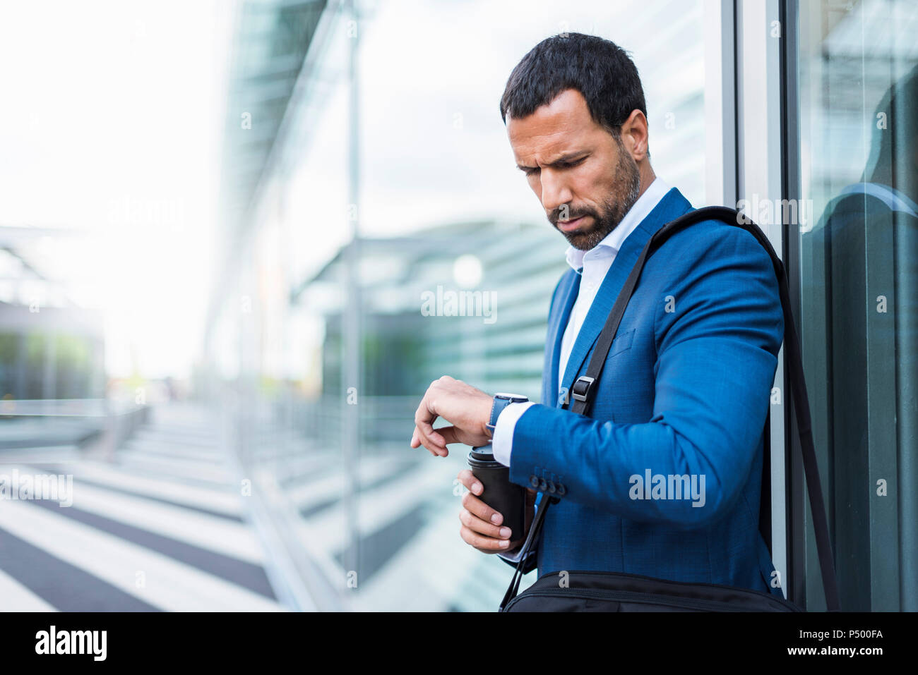 Geschäftsmann mit Tasse Kaffee, schaut auf seine Uhr Stockfoto