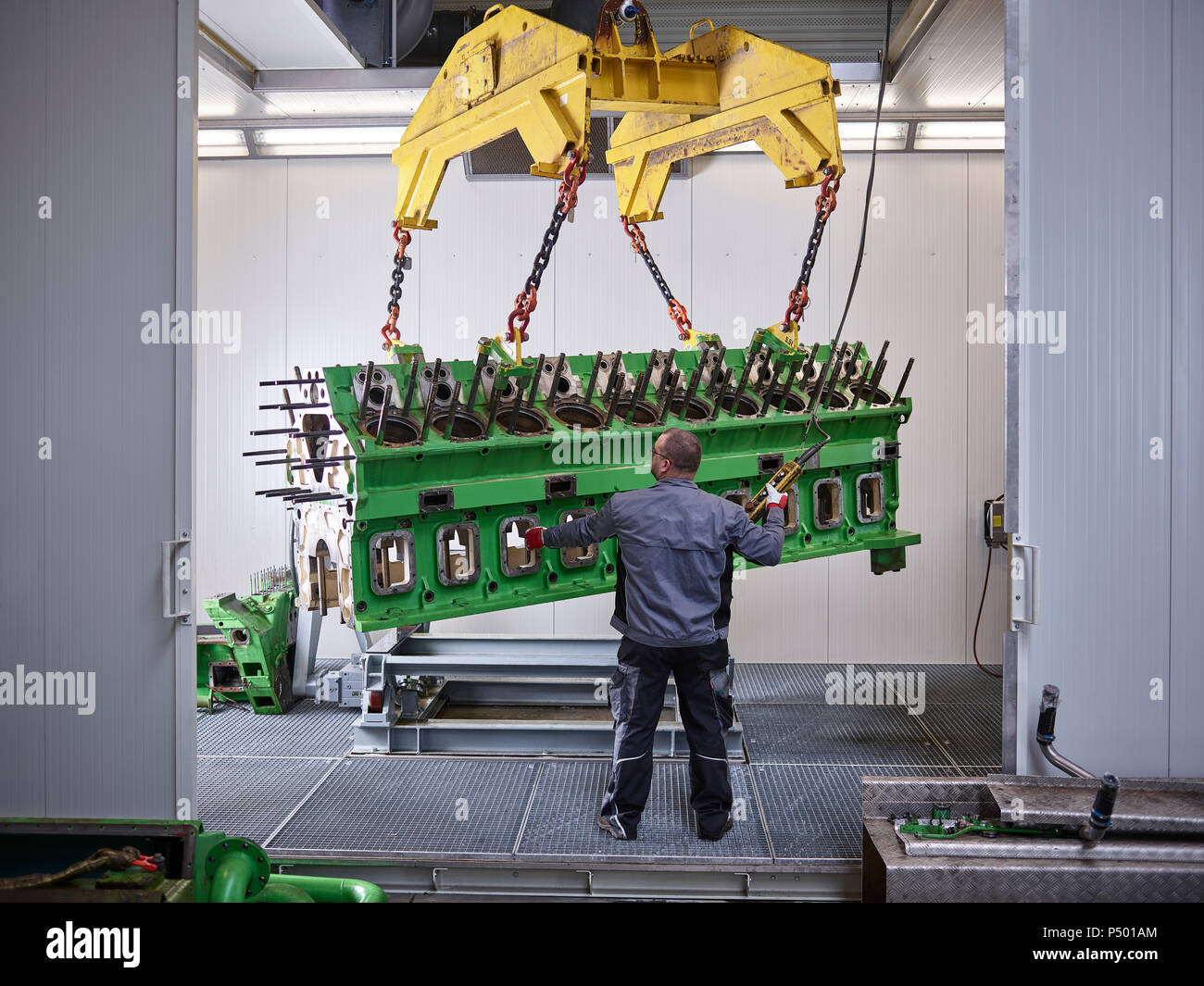 Arbeiter in der Fabrik heben Motorblock mit Kran Stockfoto