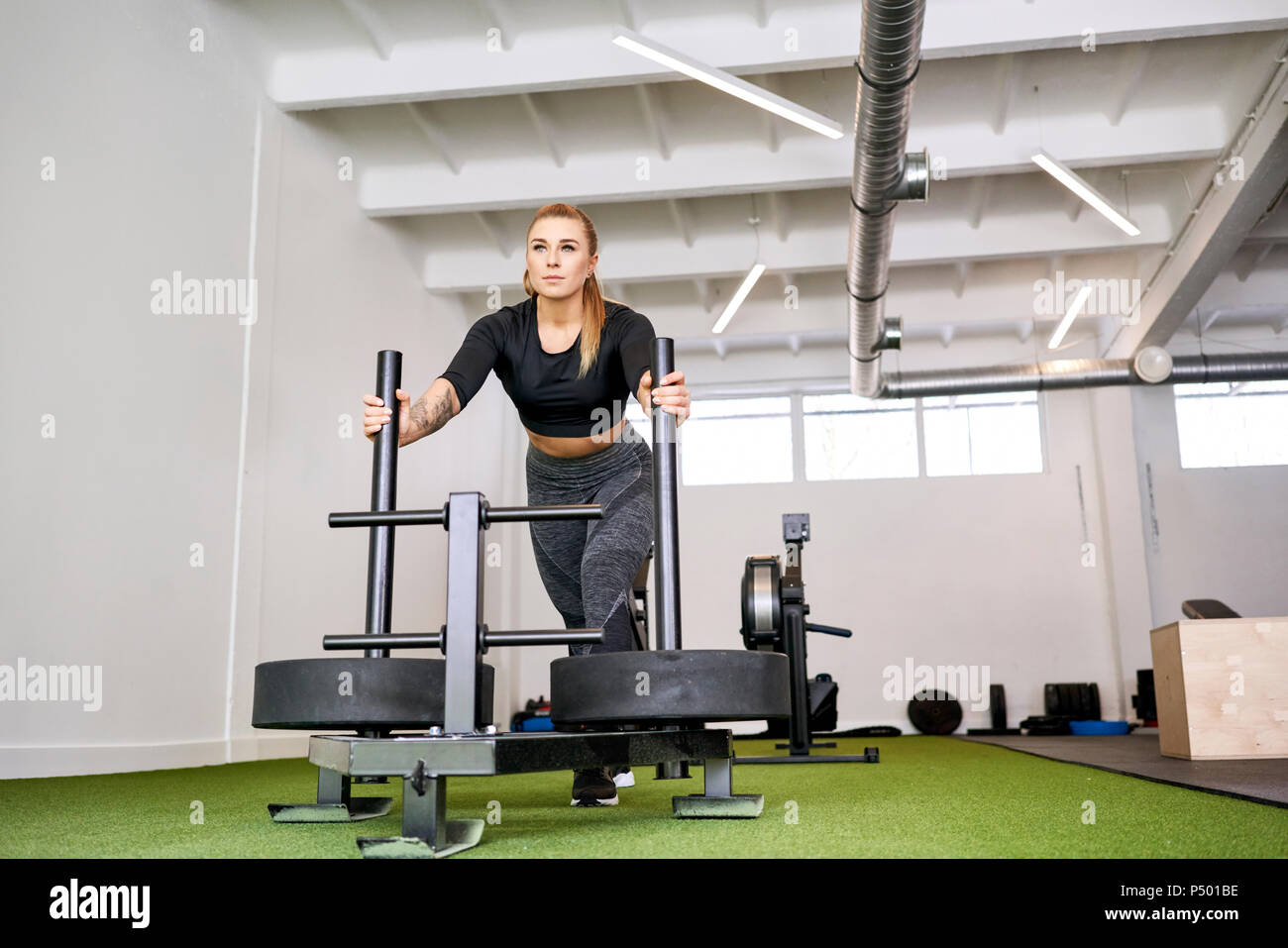 Frau drücken Gewicht Schlitten im Fitnessstudio Stockfoto